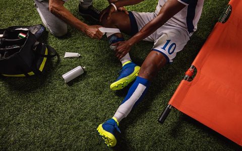 Soccer player injured knee during the game. Sport Doctors provide first aid to player on a professional football field. Close up